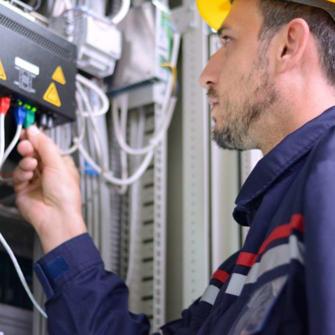 Engineer inspecting cabling connection in electrical room.